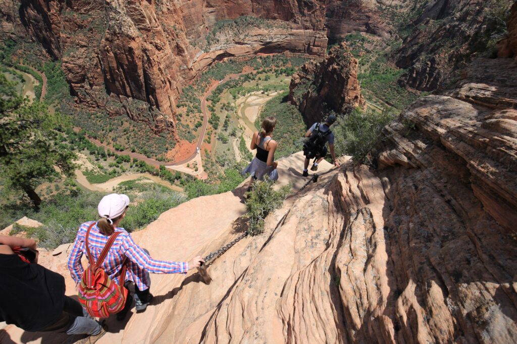 Several hikers walking down a rock path with a steep drop-off to the side