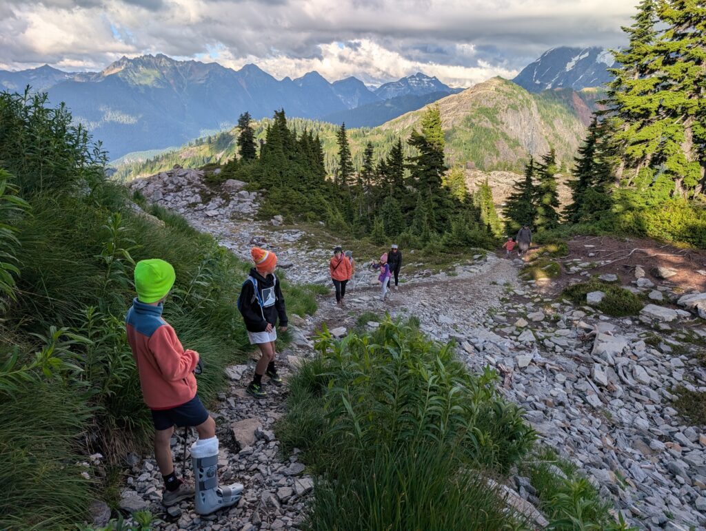 A group of hikers looking away at mountains along a dirt and stone path