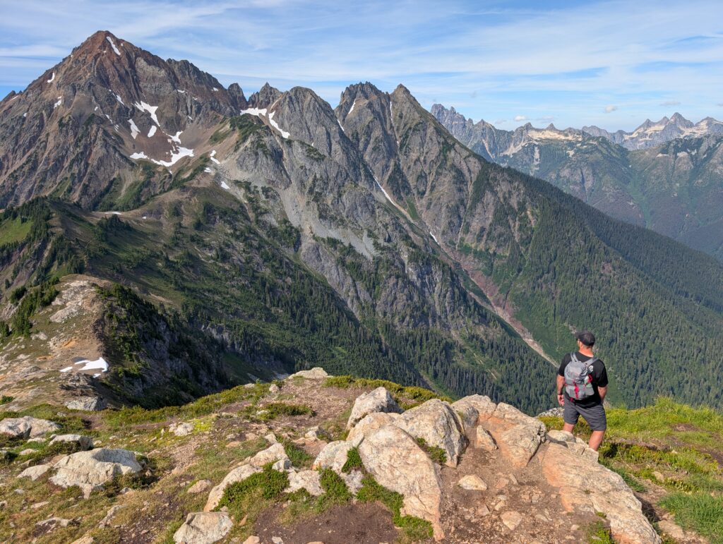A man looking at the highest peak in a series of jagged mountains