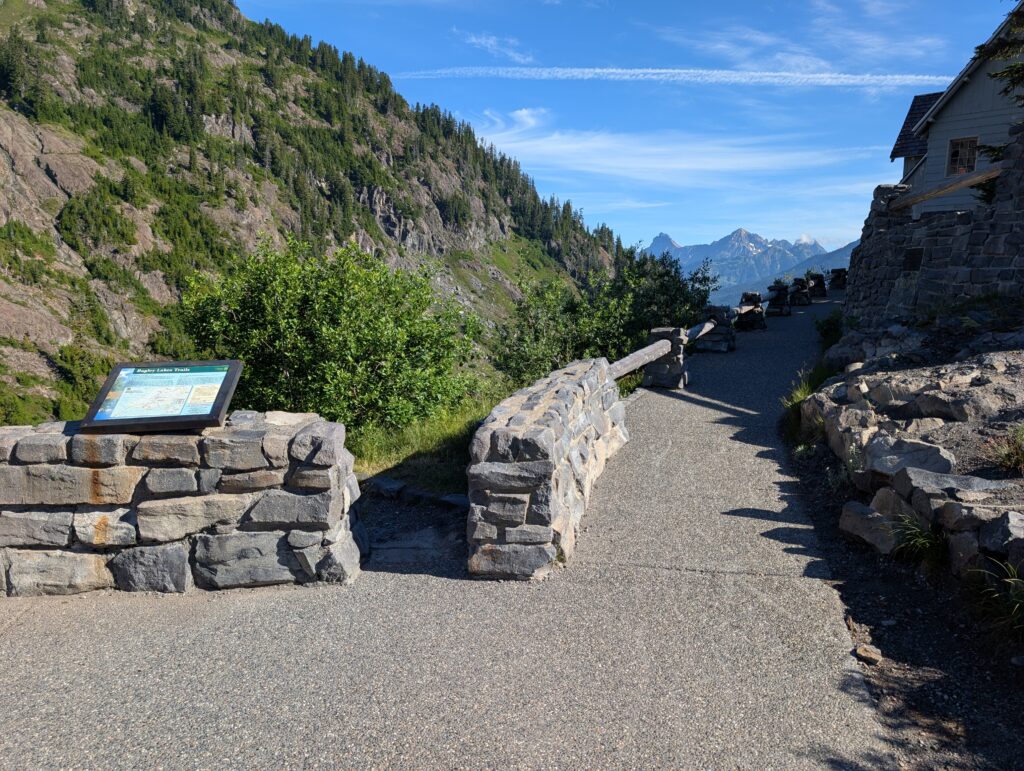 A rock wall and paved path leading up to a building with mountains in the far distance