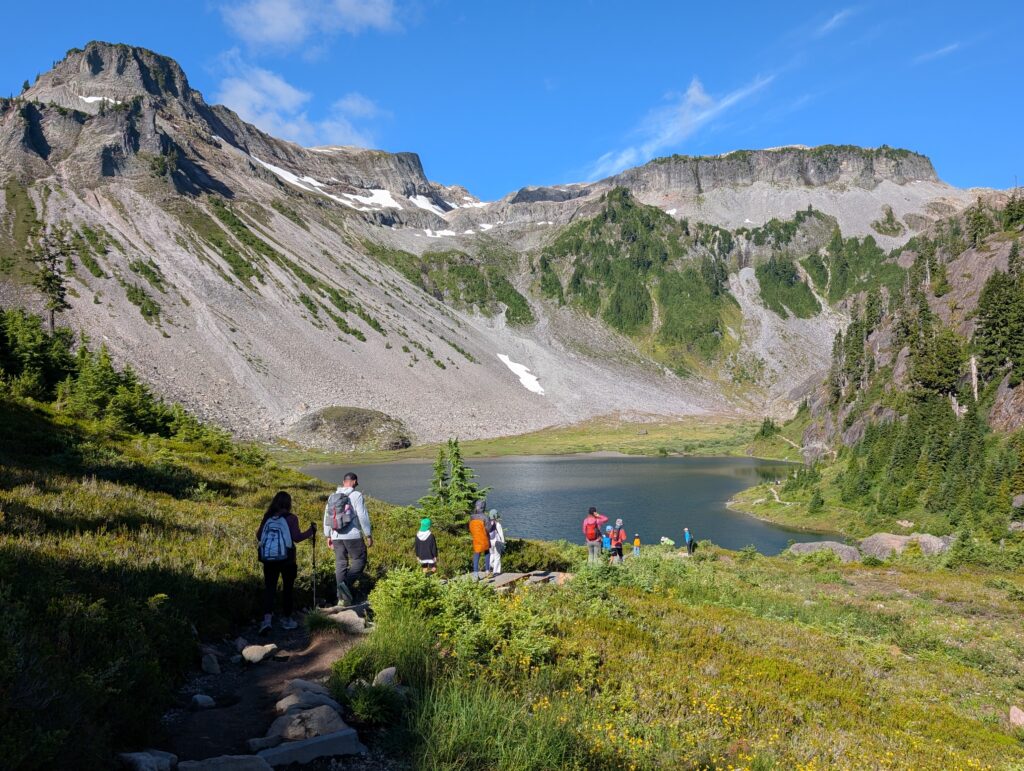 A group of hikers walking down towards a bowled-in lake