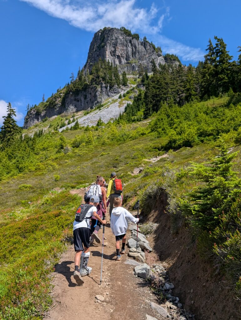Hikers following a dirt path towards a prominent peak jutting out of the landscape