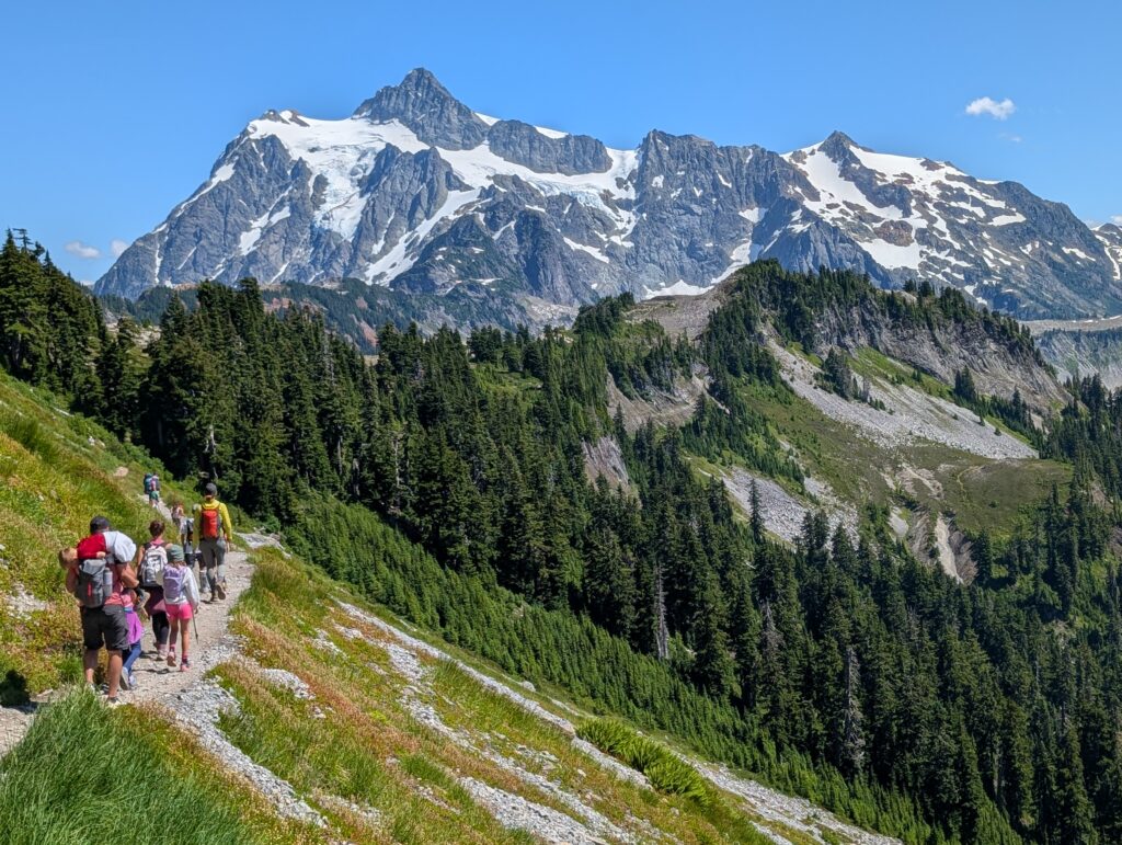 People walking along a stone trail towards a huge mountain face by Artist Point