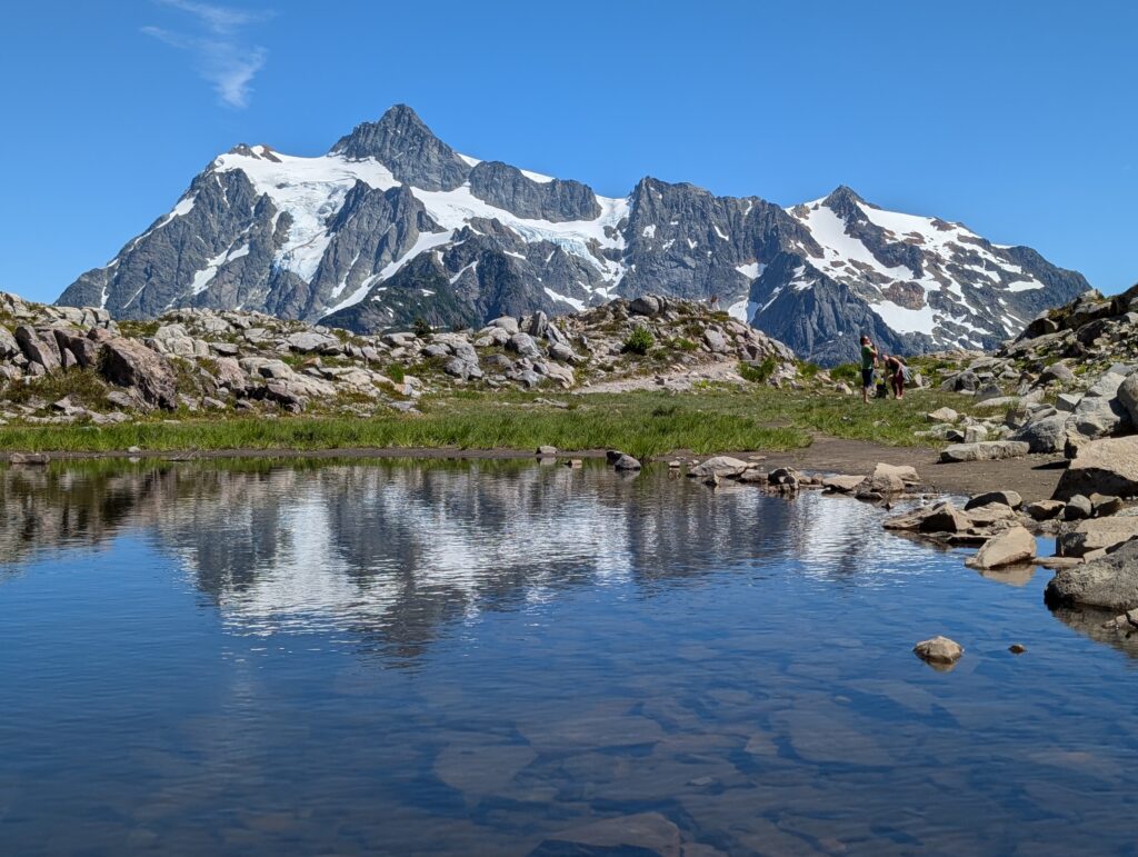 An elongated, snow-capped mountain formation with a partial reflection in a body of water